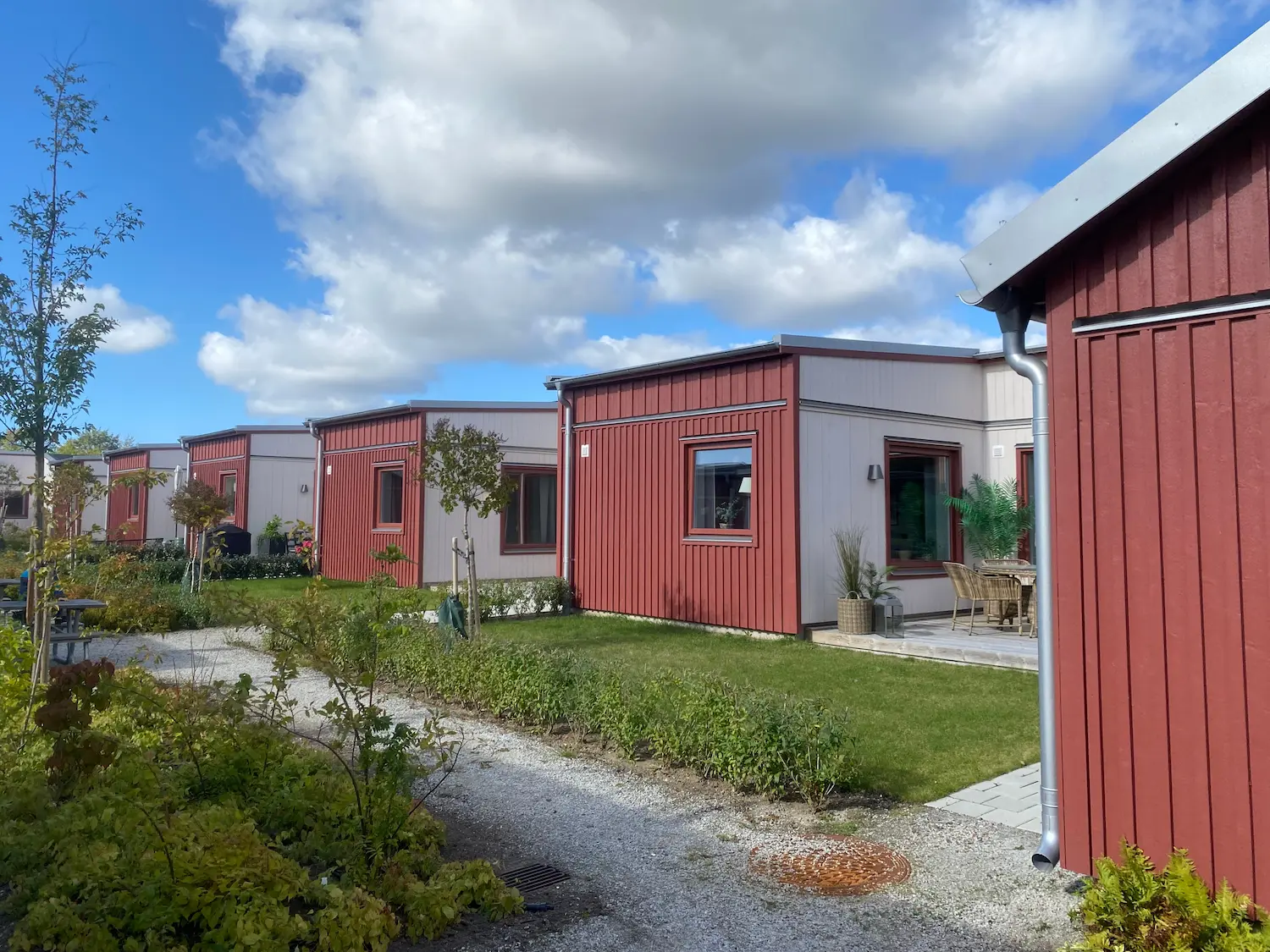 Röda och vita bostäder vid en grön gård med gångstråk
